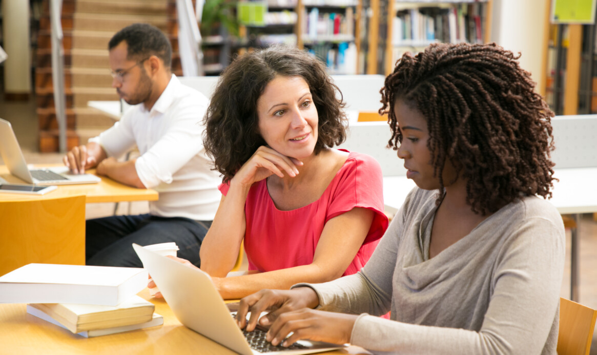 Cheerful women working with laptop at public library