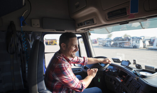 Professional truck driver with smile driving truck and delivering goods on time.